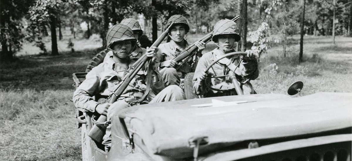 4 Japanese American Soldiers with weapons sitting in a jeep