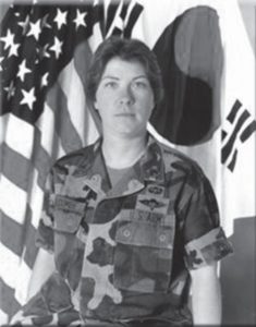 Jeanne Balcombe in uniform with the American and Republic of Korea flags behind her