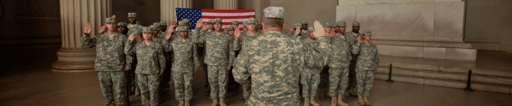 Soldiers in formation raising their right hand with an American flag behind the formation