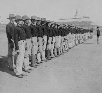 Line of Soldiers in late 19th century uniforms with a Spanish castle in the distance