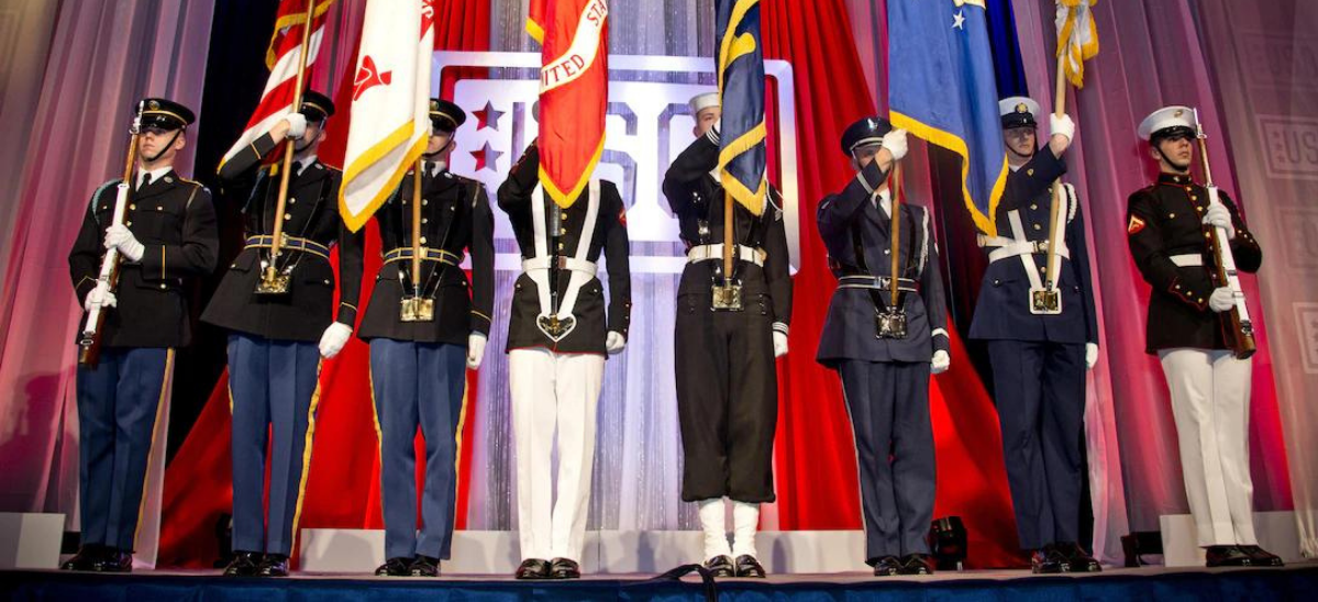 Military Color Guard with service members from each branch holding their branches flag.