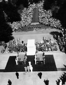 Aerial view of the tomb surrounded by a large crowd. At the foreground are two caskets draped with American flags, flanked by servicemembers from various Armed Services branches