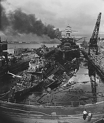 Two heavily damaged ships sit in a shipyard.