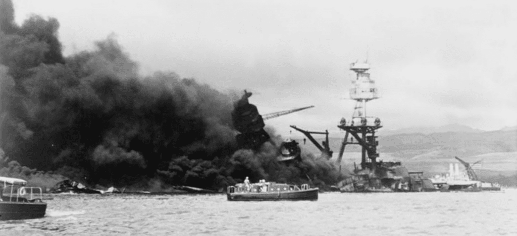 small boat in the foreground with listing and burning ships in the background