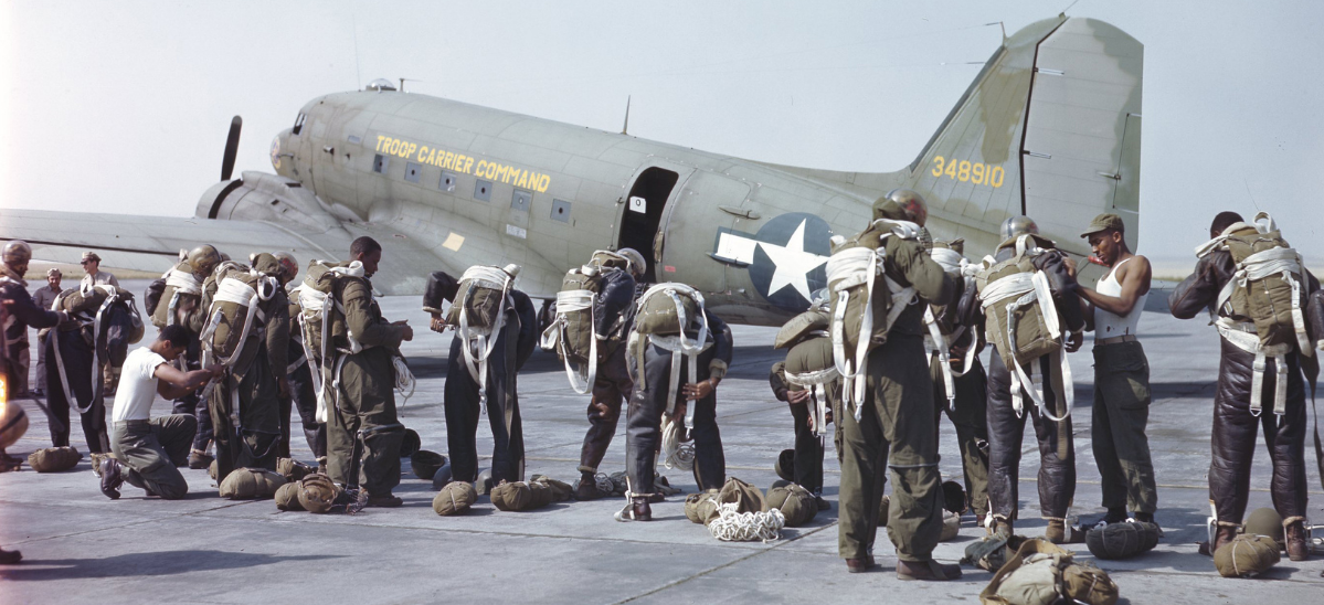 A group of paratroopers in full gear prepare to board an airplane