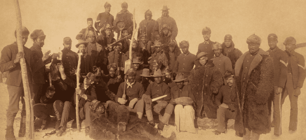 Group of mostly Black soldiers posed in late 19th century era uniforms