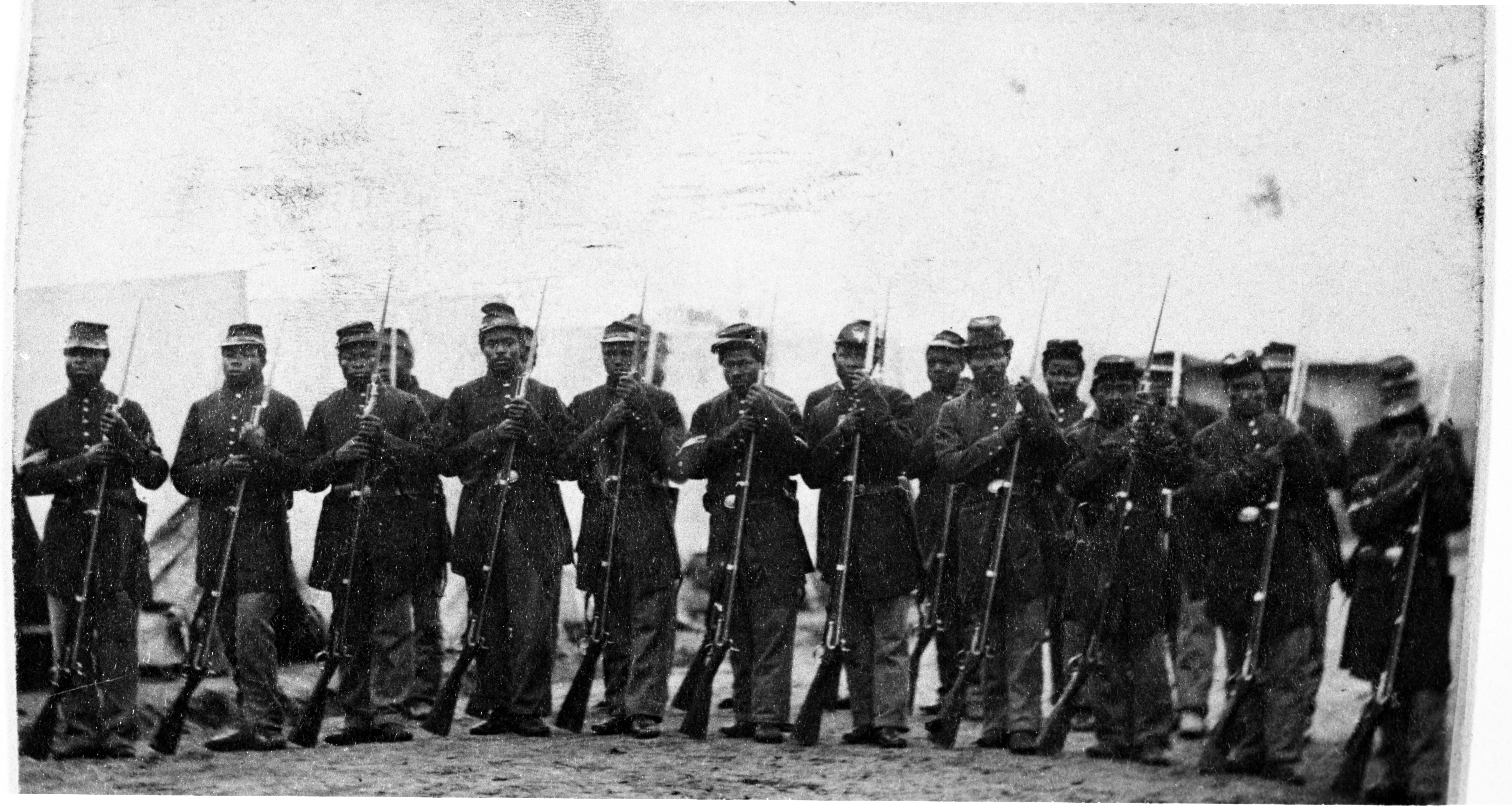 Group of Black Soldiers in Civil War era uniforms standing in formation with their weapons