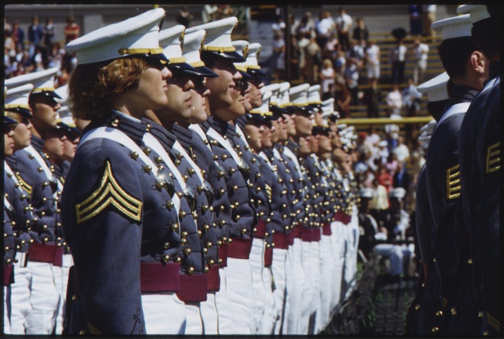 Rows of cadets stand in a field at graduation.