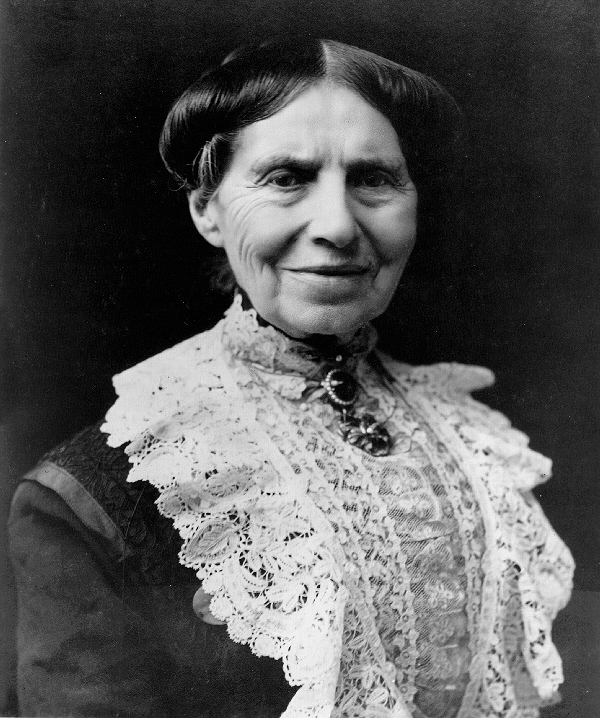 An elderly Clara Barton, head and shoulders, wearing an elaborate lace collar and an amethyst broach. 