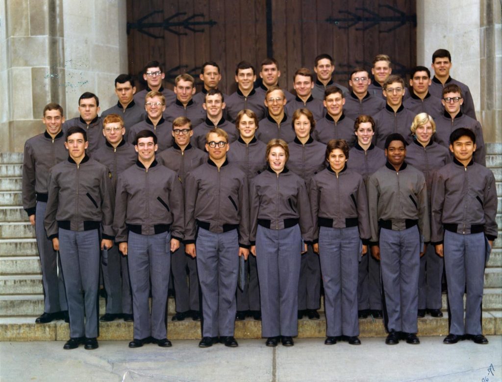 A group of cadets stand in formation on the steps of a building. 