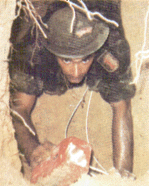 man in uniform crawling through a tunnel holding a brick.