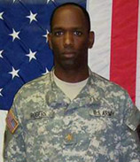 Alan Rogers in uniform standing in front of an American flag, head and shoulders. 