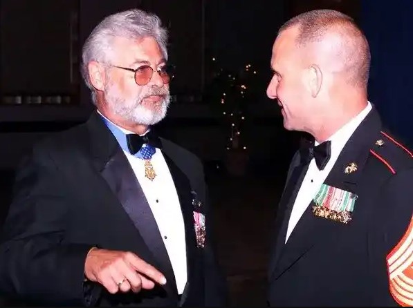 Jon Cavaiani in a tuxedo wearing his Medal of Honor talking to a U.S. Marine Sergeant Major. 