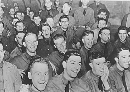 Soldiers in uniform laugh and smile together. 