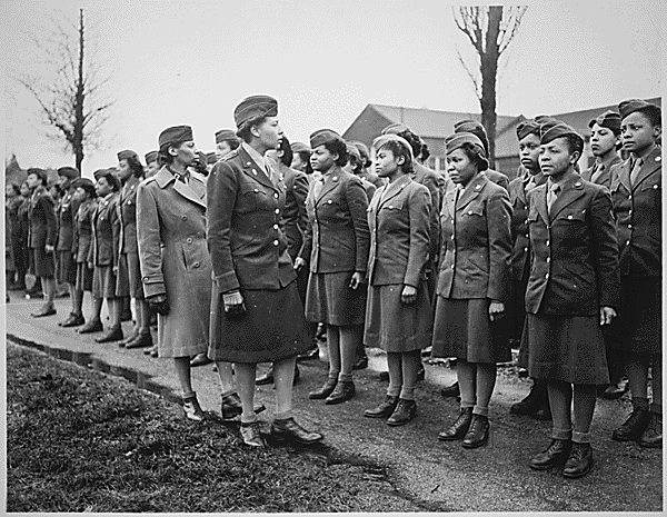 Two Black female officers inspect a line of Black female soldiers. 