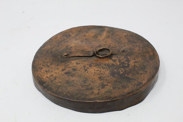 One copper alloy pot lid with lift ring and stamped makers mark. Found during the restoration of Fort Ticonderoga in the early 20th century. Object ID 2020.2.3. Courtesy of The Fort Ticonderoga Museum Collection.