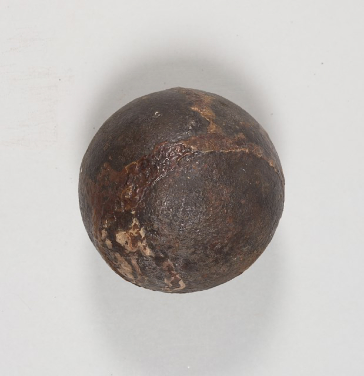 Strapped shot or fixed shot, ca. 1776-1781. This ammunition was designed for a British 3-pounder cannon. The cannonball would have been attached to the wooden base. The wooden base would also have had a bag of gunpowder tied to it. The grooves in the wooden base show where the straps holding the cannonball and the bag of gunpowder would have been. Object ID 2024.7.7a-b. Courtesy of the Fort Ticonderoga Museum Collection.